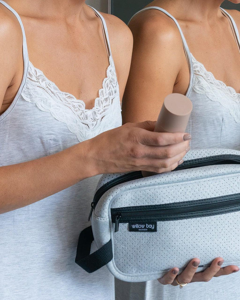 Light marle neoprene cosmetic bag with black zipper and strap, held by a woman in a grey lace camisole.