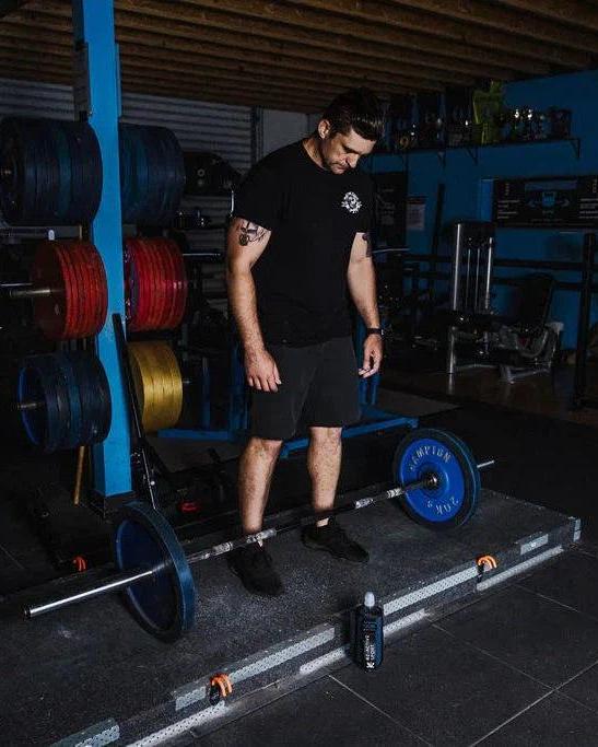 Academy Blue magnetic gym caddy next to a barbell in a gym, keeping essentials secure.