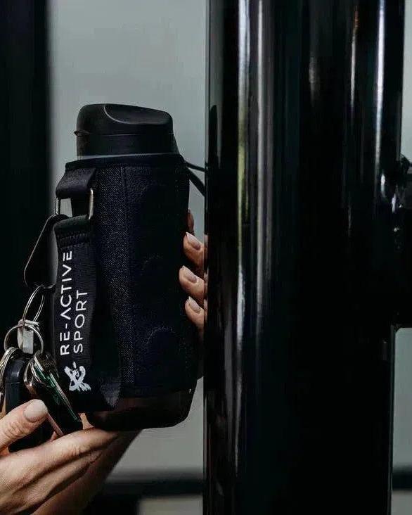 Black denim Magnetic Gym Caddy holding a water bottle and keys, attached to gym equipment.