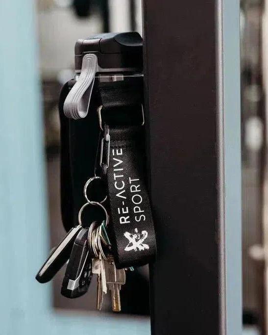 Jet black Magnetic Gym Caddy with keys and a "Re-Active Sport" strap, securely attached to steel gym equipment.