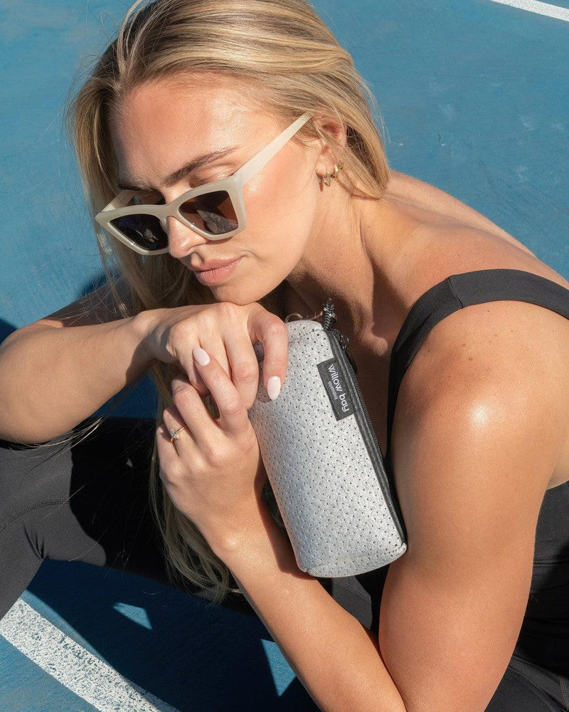 Woman holding a light marle perforated neoprene wristlet clutch with a black zipper and strap.