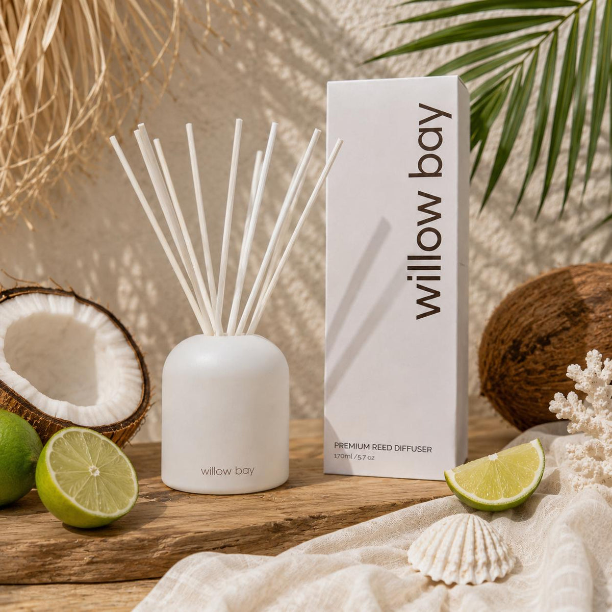 White Willow Bay Coastal Coconut reed diffuser with reeds, packaging, coconuts, limes, and seashells.