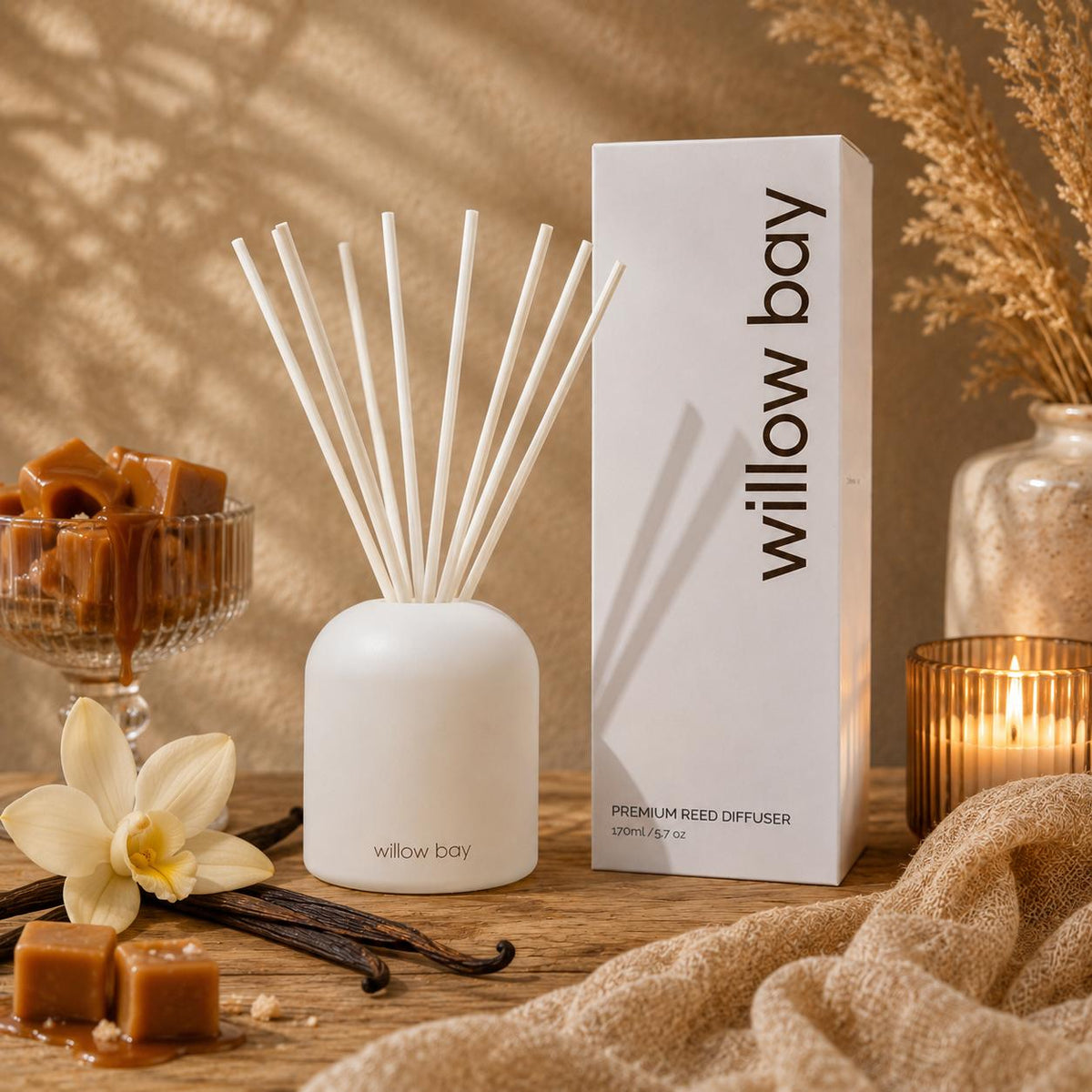 White Willow Bay reed diffuser with vanilla caramel scent, reeds, elegant box, and candle on wood.